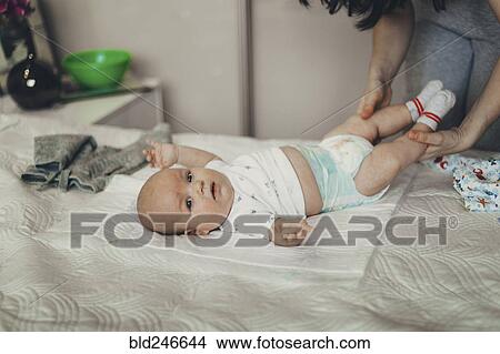 Caucasian mother changing diaper of baby son on bed View Large Photo Image Picture - Caucasian mother changing diaper of baby son on bed. Fotosearch