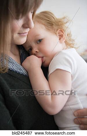 Caucasian mother holding daughter sucking thumb View Large Photo Image Stock Photo - Caucasian mother holding daughter sucking thumb. Fotosearch