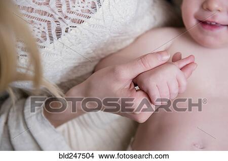 Picture - Caucasian mother holding hand of baby son. Fotosearch
