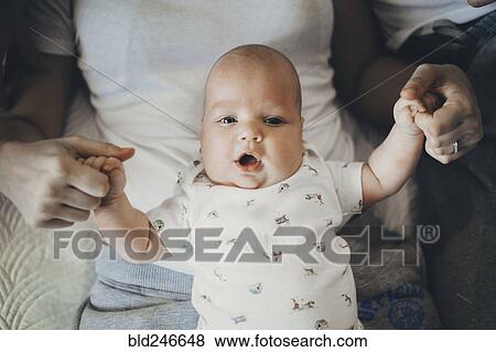 Stock Photo - Caucasian mother holding hands of baby son in lap. Fotosearch