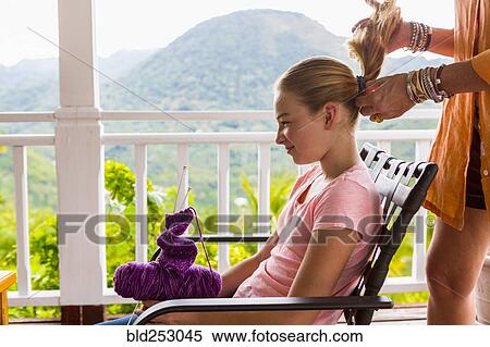 Stock Photography - Caucasian mother holding ponytail of daughter. Fotosearch