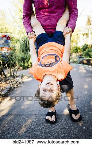 Stock Photo - Caucasian mother holding son upside-down. Fotosearch