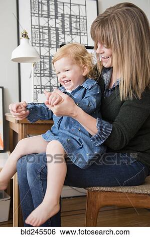 Stock Photograph - Caucasian mother playing with daughter sitting in lap. Fotosearch