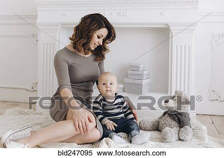 Stock Photography - Caucasian mother sitting on floor with baby son. Fotosearch