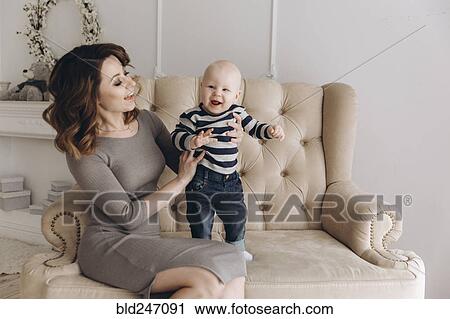 Caucasian mother sitting on love seat playing with baby son View Large Photo Image Stock Image - Caucasian mother sitting on love seat playing with baby son. Fotosearch