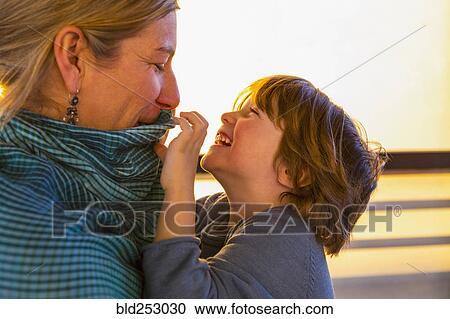 Stock Image - Caucasian mother watching son play with her collar. Fotosearch