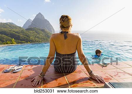 Stock Image - Caucasian mother watching son swimming. Fotosearch