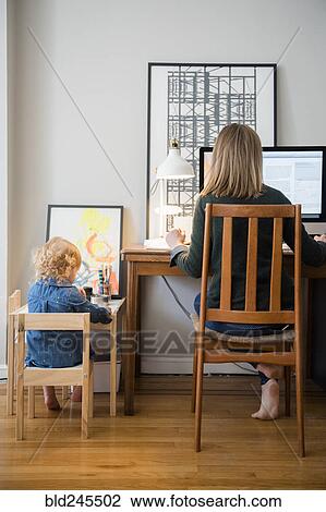 Caucasian mother working and daughter playing in home office View Large Photo Image Stock Image - Caucasian mother working and daughter playing in home office. Fotosearch