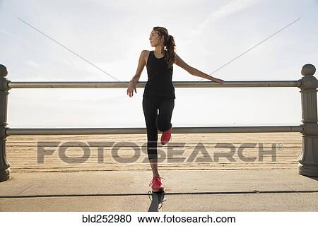 Stock Image - Caucasian teenage girl leaning on railing at beach. Fotosearch