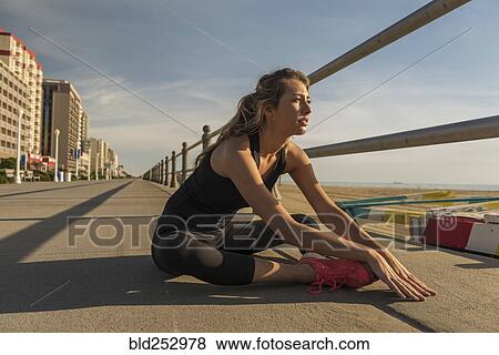 Caucasian teenage girl sitting on boardwalk stretching legs View Large Photo Image Stock Photo - Caucasian teenage girl sitting on boardwalk stretching legs. Fotosearch