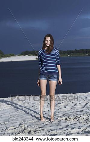 Picture - Caucasian teenage girl standing on beach. Fotosearch