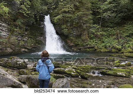 Picture - Caucasian woman admiring distant waterfall. Fotosearch