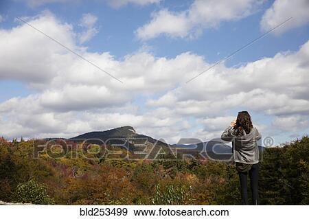Stock Photo - Caucasian woman admiring mountain range in autumn. Fotosearch