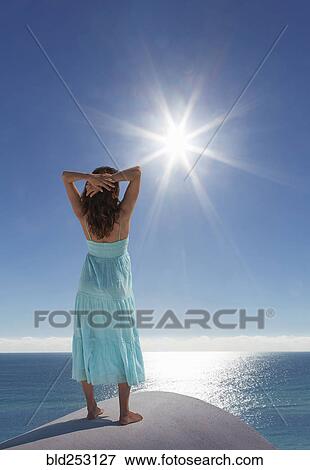 Stock Photo - Caucasian woman admiring scenic view of sunny ocean. Fotosearch