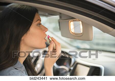 Caucasian woman applying lipstick in car View Large Photo Image Stock Image - Caucasian woman applying lipstick in car. Fotosearch