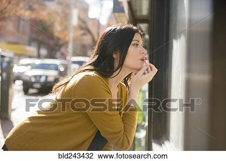 Caucasian woman applying lipstick in city View Large Photo Image Stock Image - Caucasian woman applying lipstick in city. Fotosearch
