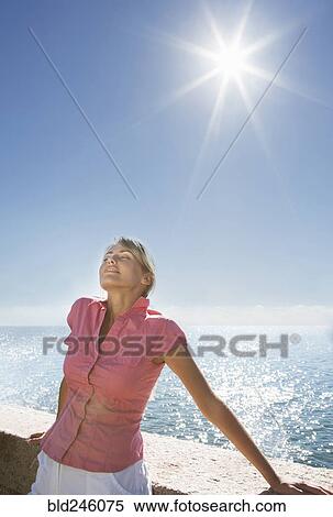 Stock Photography - Caucasian woman basking in sunshine near ocean. Fotosearch
