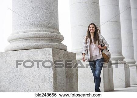 Stock Photograph - Caucasian woman carrying backpack at school. Fotosearch