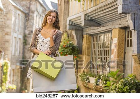 Stock Photo - Caucasian woman carrying shopping bags in city. Fotosearch