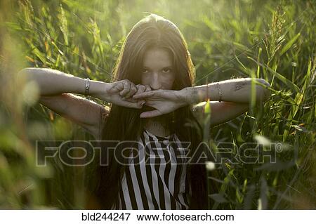 Stock Photo - Caucasian woman covering mouth with hands in field. Fotosearch