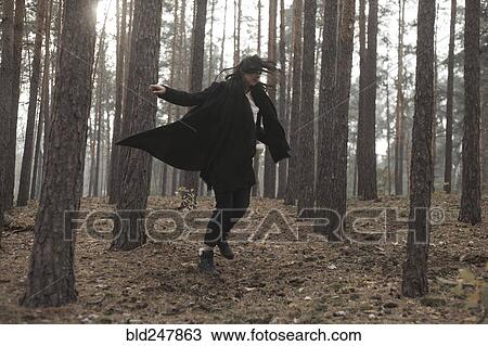Stock Image - Caucasian woman dancing in forest. Fotosearch