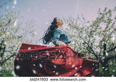 Stock Image - Caucasian woman dancing near flowering trees. Fotosearch