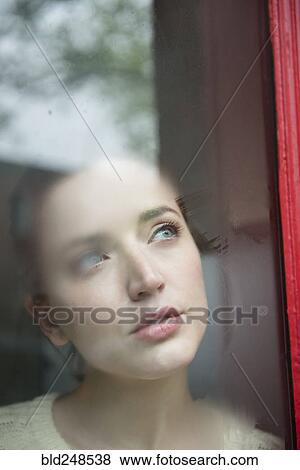 Stock Photo - Caucasian woman daydreaming behind foggy window. Fotosearch