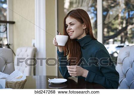 Stock Photo - Caucasian woman drinking coffee at restaurant. Fotosearch