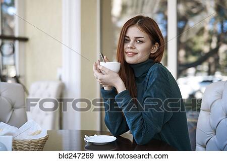 Stock Photo - Caucasian woman drinking coffee at restaurant. Fotosearch