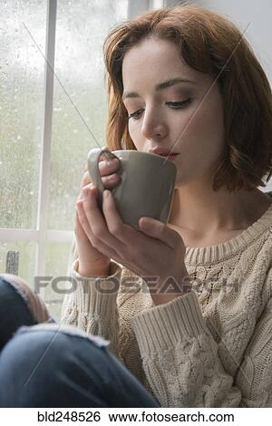 Caucasian woman drinking coffee near rainy window View Large Photo Image Stock Photograph - Caucasian woman drinking coffee near rainy window. Fotosearch