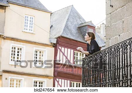 Caucasian woman drinking coffee on balcony in city View Large Photo Image Picture - Caucasian woman drinking coffee on balcony in city. Fotosearch
