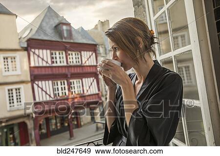Caucasian woman drinking coffee on balcony in city View Large Photo Image Stock Photo - Caucasian woman drinking coffee on balcony in city. Fotosearch