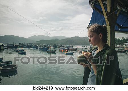 Stock Photo - Caucasian woman drinking milk from coconut with straw. Fotosearch