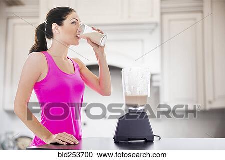 Caucasian woman drinking smoothie in kitchen View Large Photo Image Stock Image - Caucasian woman drinking smoothie in kitchen. Fotosearch