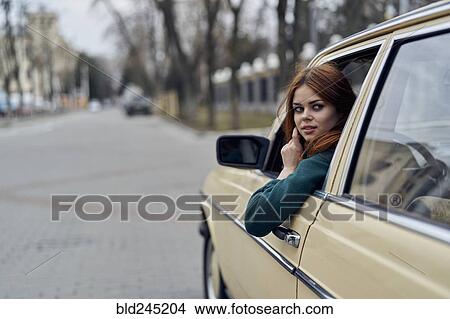 Picture - Caucasian woman driving car looking over shoulder. Fotosearch