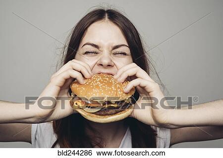 Stock Photograph - Caucasian woman eating cheeseburger. Fotosearch