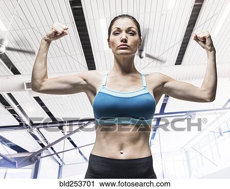 Stock Image - Caucasian woman flexing arm muscles. Fotosearch