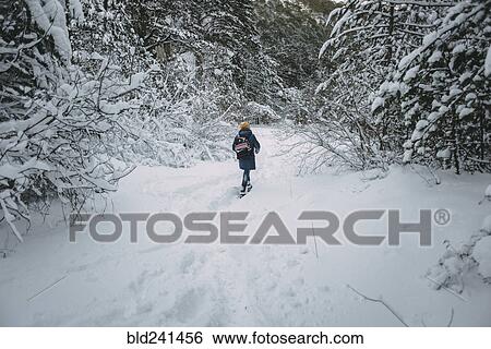 Stock Photograph - Caucasian woman hiking in snowy forest. Fotosearch