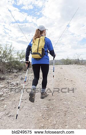 Stock Photography - Caucasian woman hiking on rocky path in desert. Fotosearch