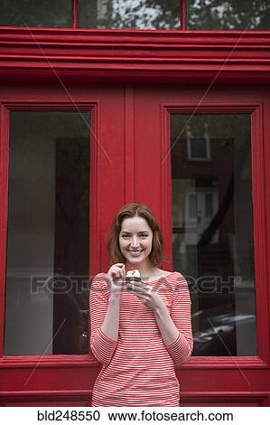 Caucasian woman holding a cupcake near red doorway View Large Photo Image Stock Image - Caucasian woman holding a cupcake near red doorway. Fotosearch