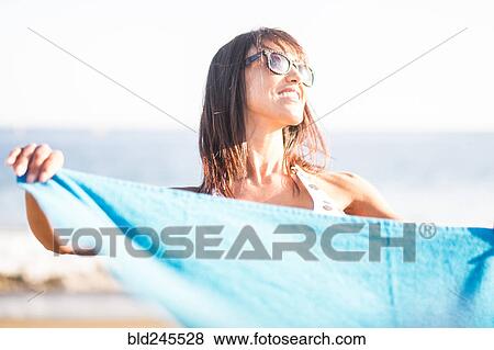 Stock Photo - Caucasian woman holding blanket on beach. Fotosearch