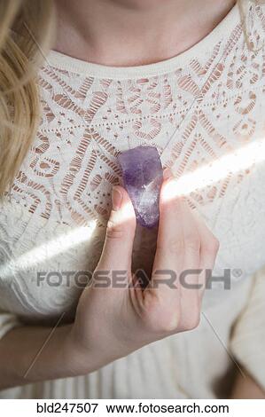 Stock Photo - Caucasian woman holding crystal to heart. Fotosearch