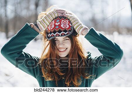 Stock Photo - Caucasian woman holding hat on head in winter. Fotosearch