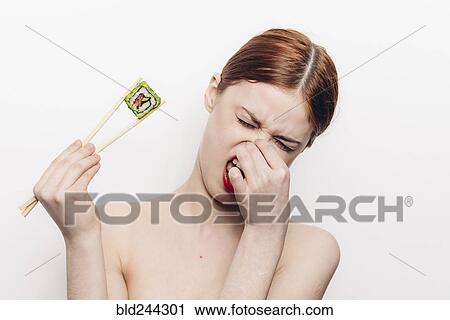 Caucasian woman holding sushi with chopsticks and holding nose View Large Photo Image Stock Image - Caucasian woman holding sushi with chopsticks and holding nose. Fotosearch