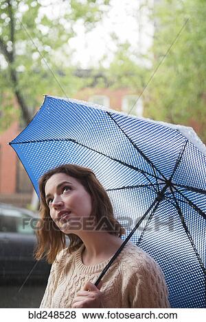 Caucasian woman holding umbrella looking up View Large Photo Image Stock Photo - Caucasian woman holding umbrella looking up. Fotosearch