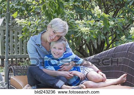 Caucasian woman hugging son on sofa outdoors View Large Photo Image Stock Photograph - Caucasian woman hugging son on sofa outdoors. Fotosearch