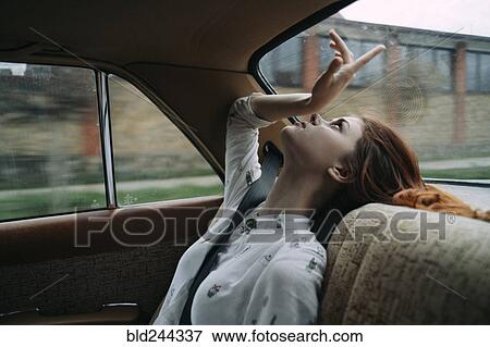 Stock Photo - Caucasian woman in back seat of car looking up. Fotosearch