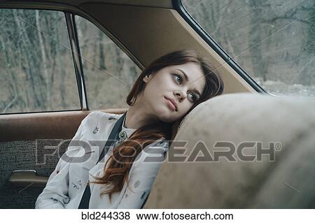 Stock Photo - Caucasian woman in back seat of car looking out window. Fotosearch