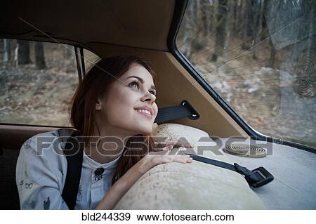 Stock Photo - Caucasian woman in back seat of car looking up. Fotosearch
