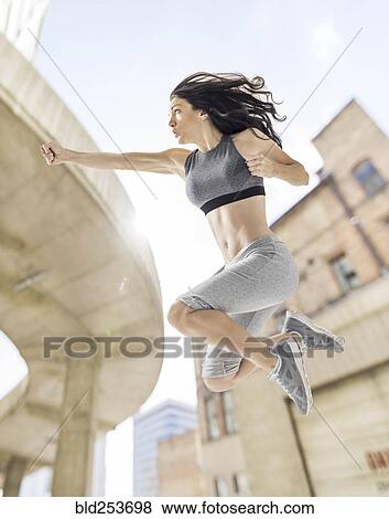 Caucasian woman jumping and punching in city View Large Photo Image Stock Photo - Caucasian woman jumping and punching in city. Fotosearch